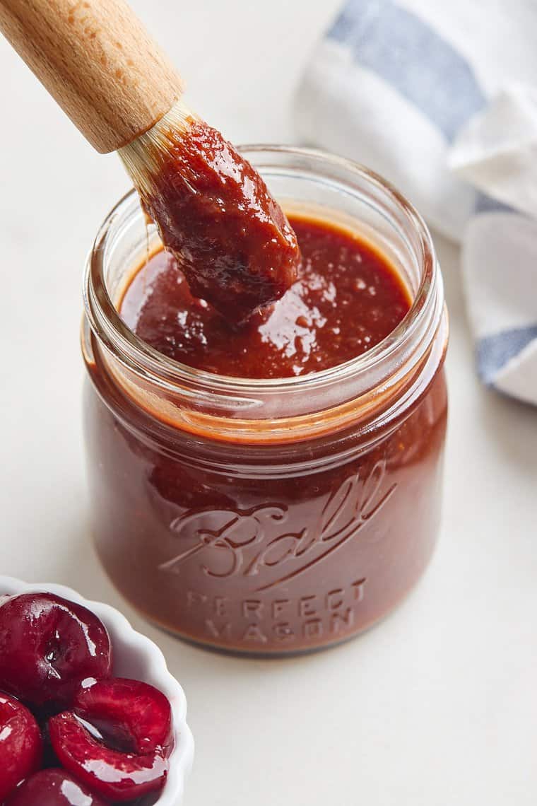 A delicious thick bbq sauce in a mason jar with a brush inside ready to serve