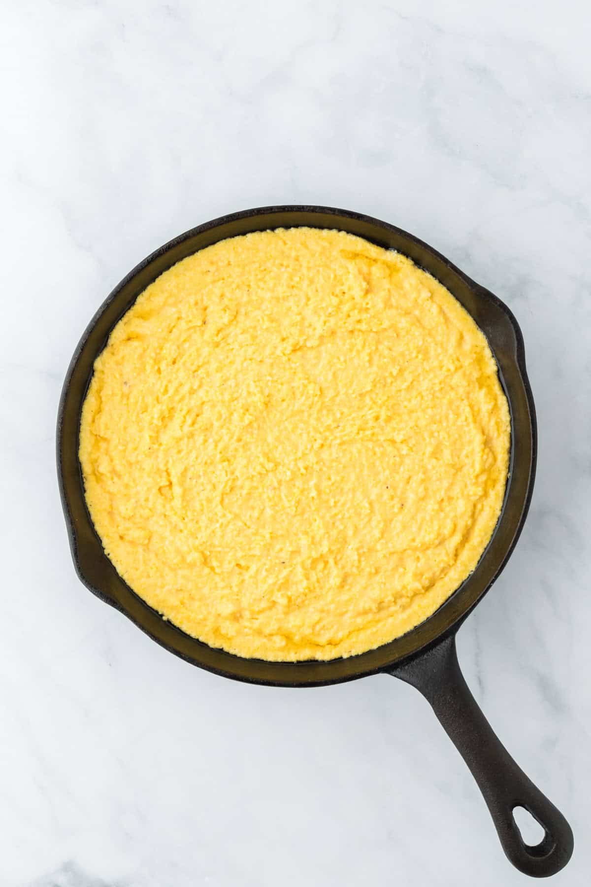 Corn pone mixture in a cast iron skillet before baking