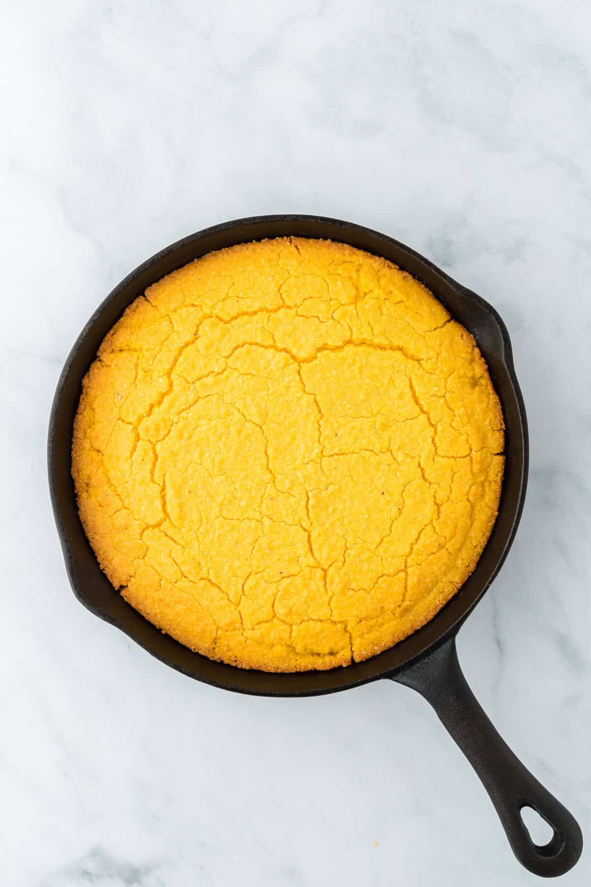 Baked corn pone in a cast iron skillet on a white background