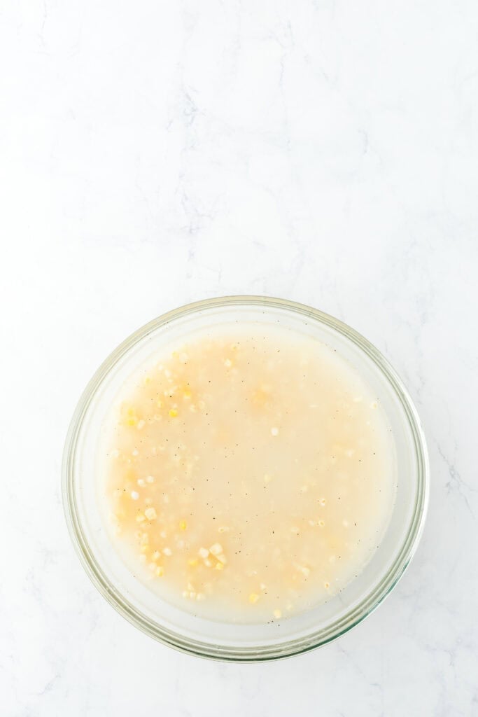 Ingredients and water in a clear bowl of fresh corn on white background