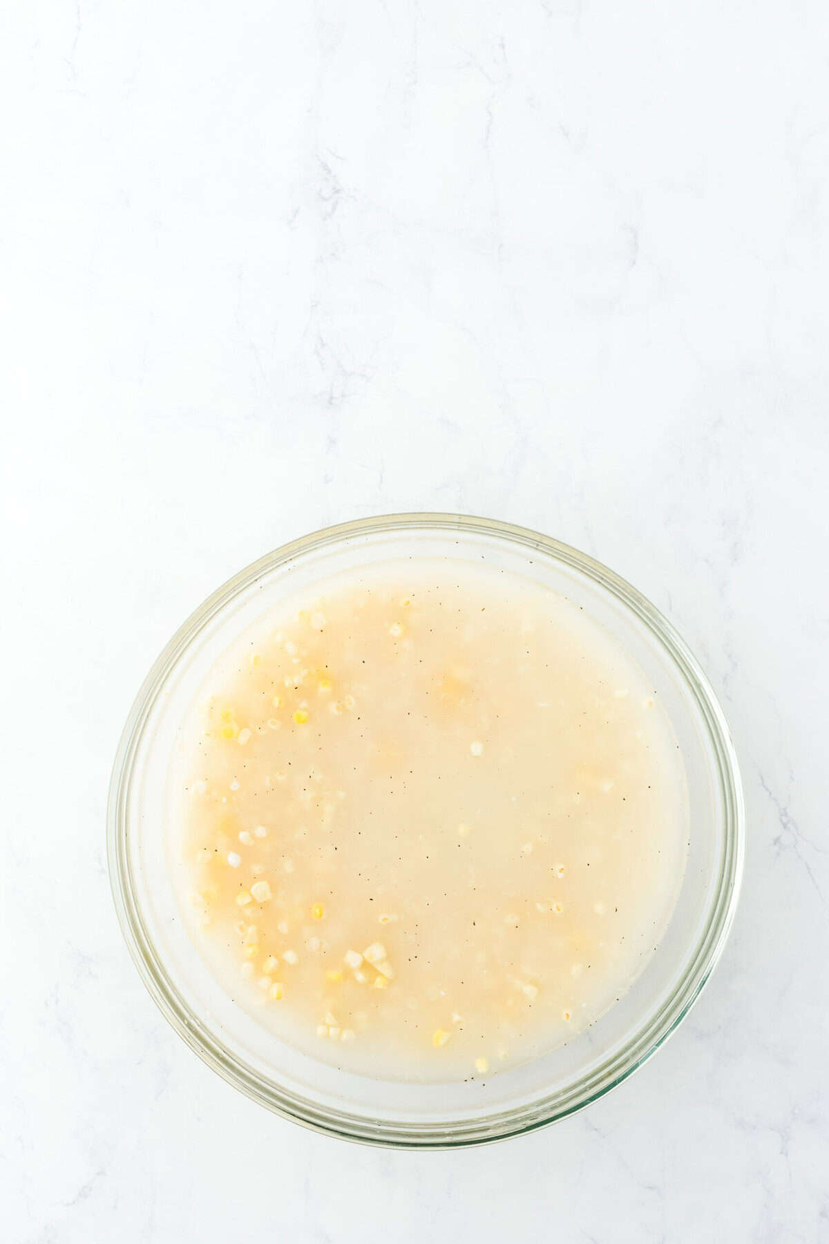 Ingredients and water in a clear bowl of fresh corn on white background