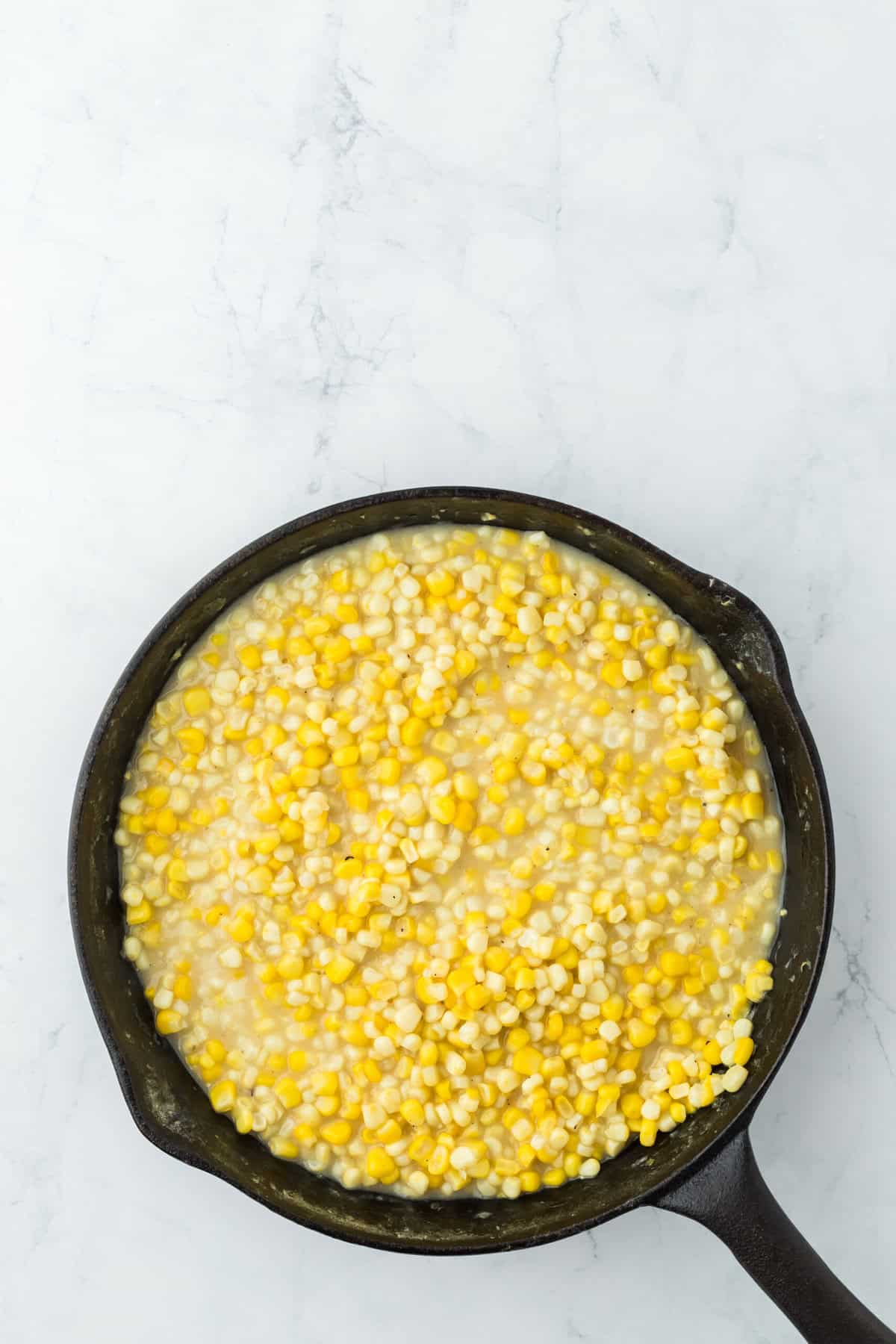 Reduced Southern fried corn in a cast iron skillet on a white background