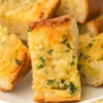 Homemade garlic bread recipe slices on a white plate on a white background