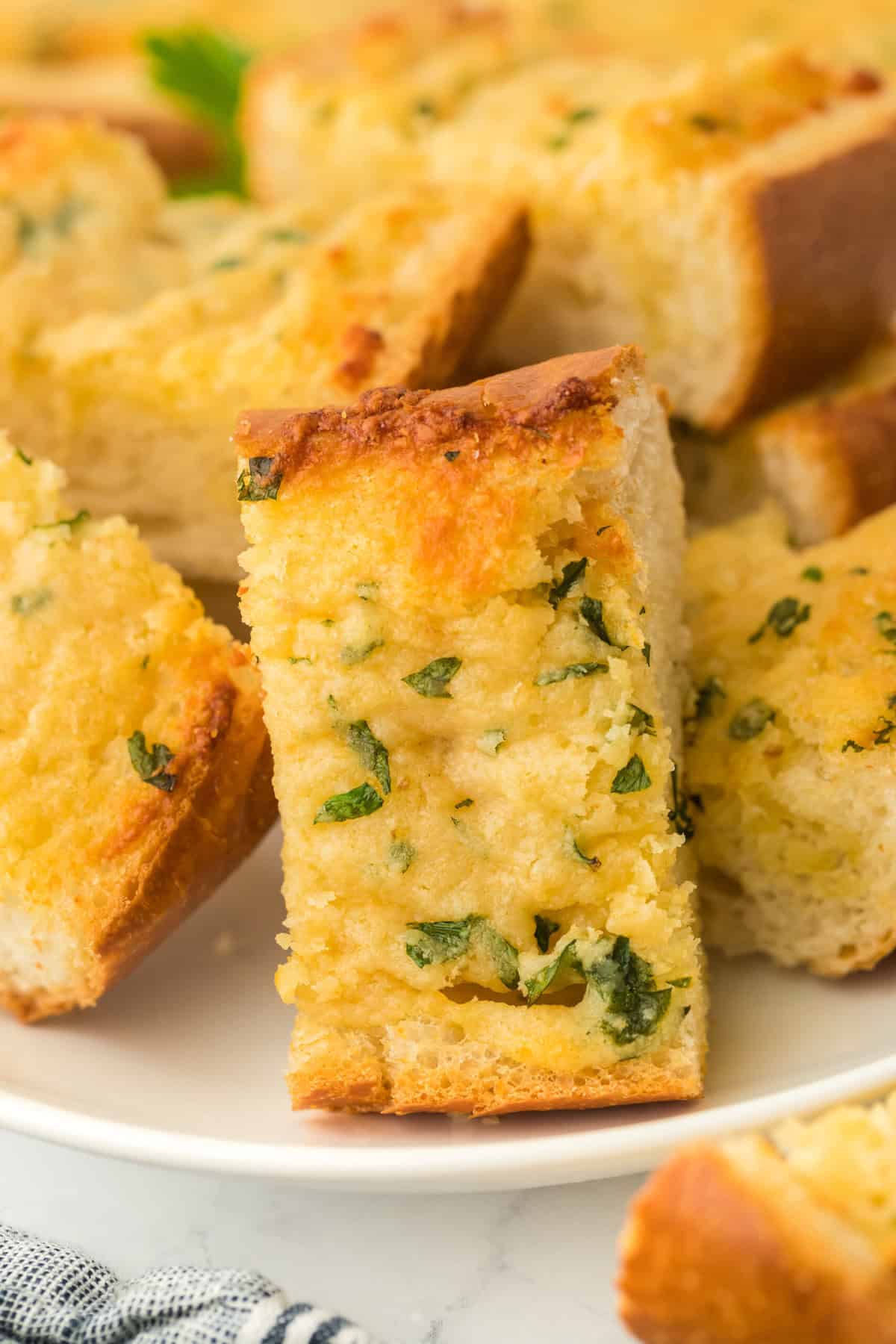 Homemade garlic bread recipe slices on a white plate on a white background