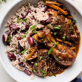Overhead shot of Jamaican Brown Stew Chicken with red beans and rice on a white plate