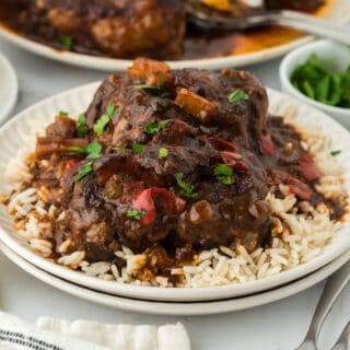 Close up of Jamaican oxtail stew served over rice, showing tender oxtail pieces and rich gravy with red bell peppers