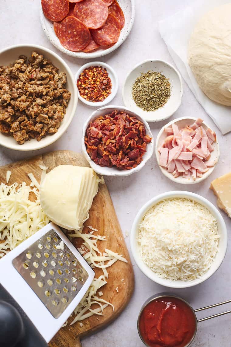 Pizza ingredients like crumbled meat, shredded cheese, spices and pizza sauce