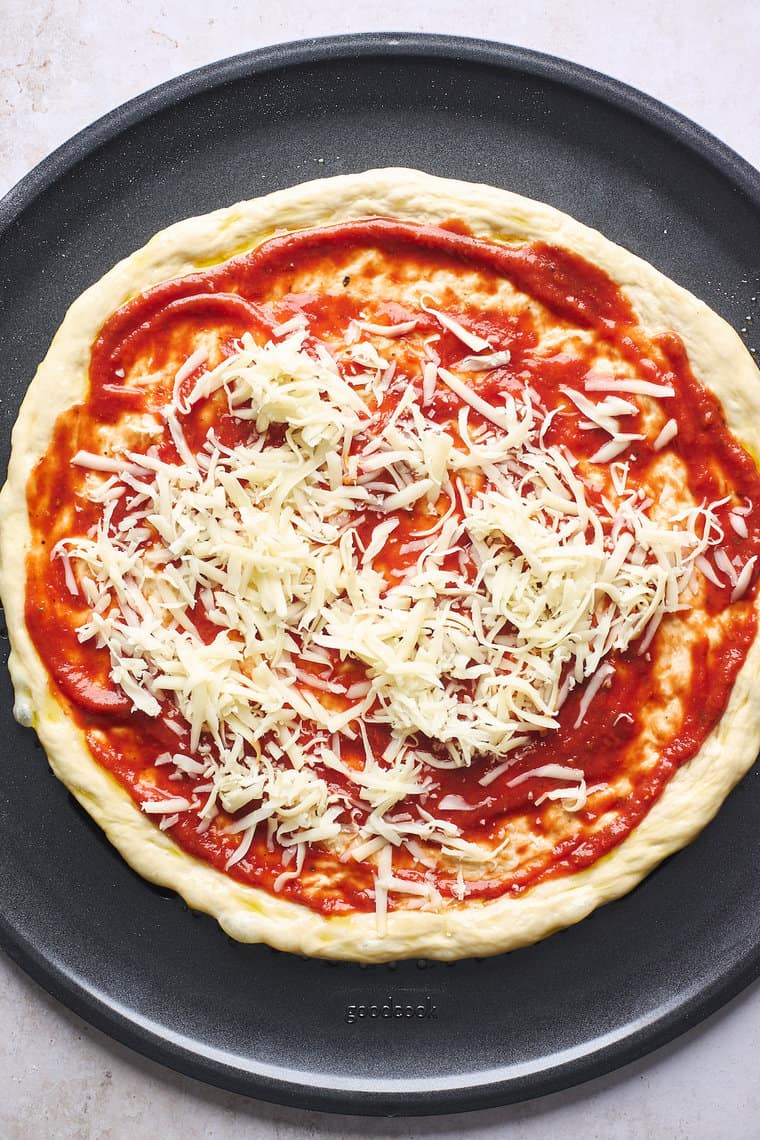Pizza dough on a pan with sauce and mozzarella