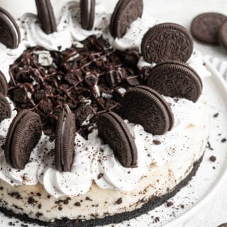 A close up of cookies and cream cheesecake with cookies on top along with whipped cream