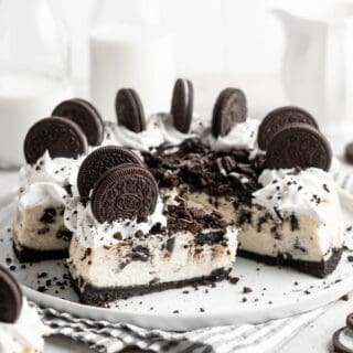 A slice of oreo cheesecake against a full cake in a white background