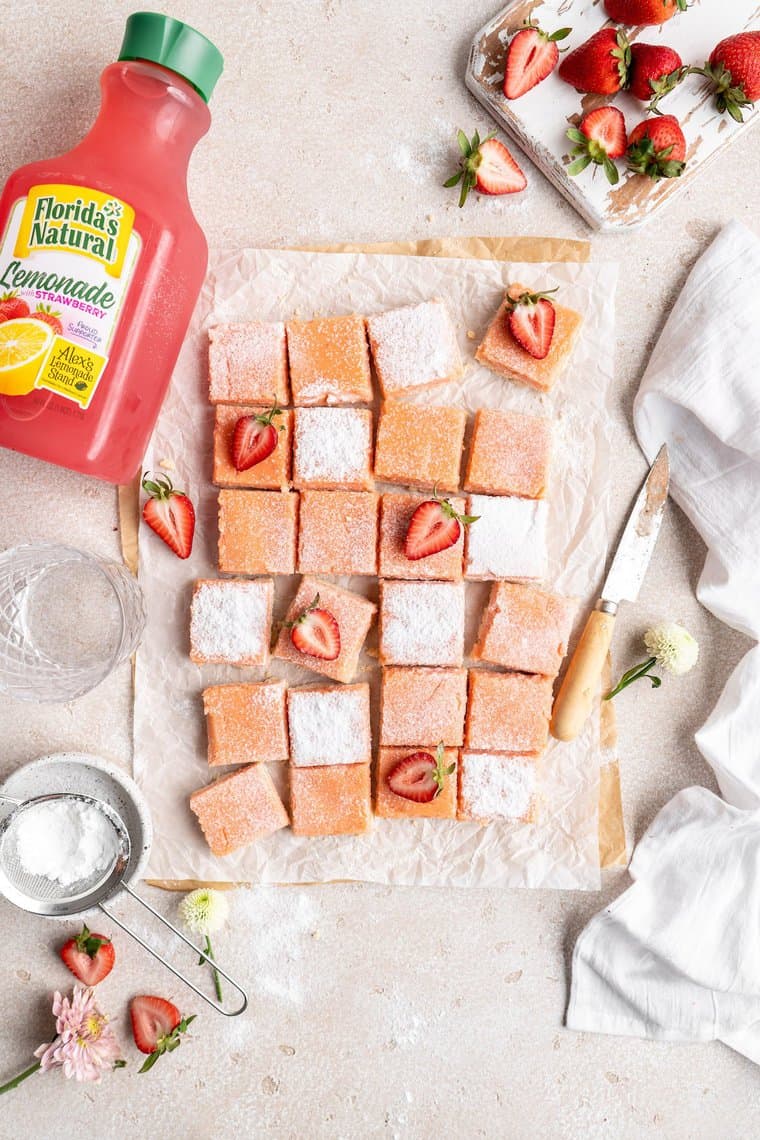 An overhead of strawberry lemon bars sliced with lemonade in the background