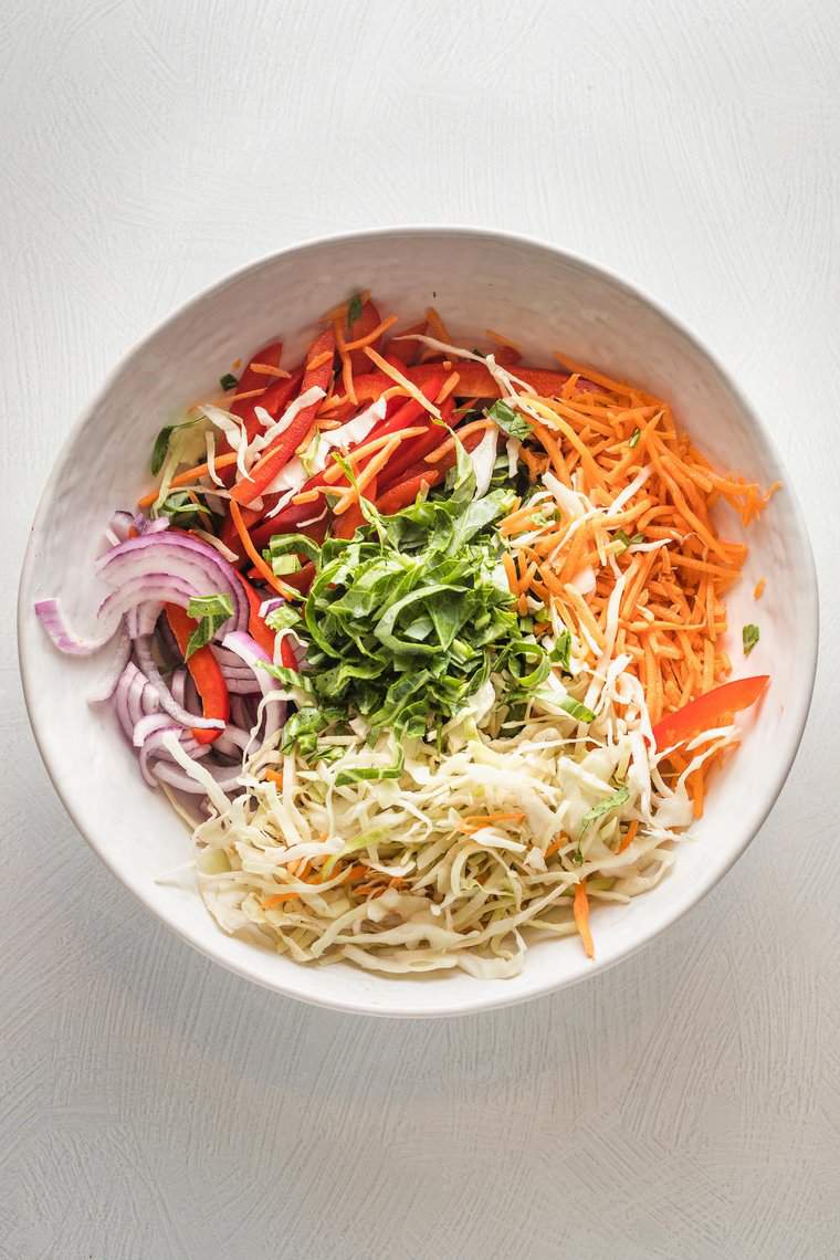 Shredded carrots, ribbons of greens, and red onion to create a coleslaw