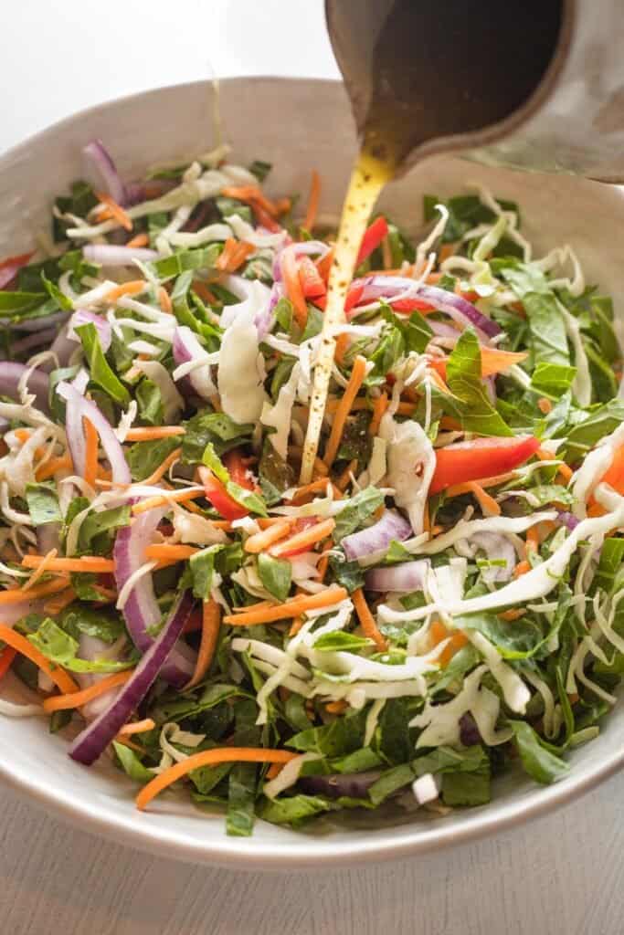Vinegar dressing being poured into a vinegar coleslaw before tossing together