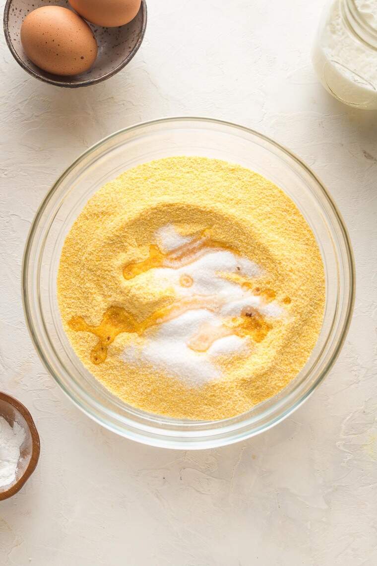 Cornmeal and dry ingredients in a clear bowl before stirring together