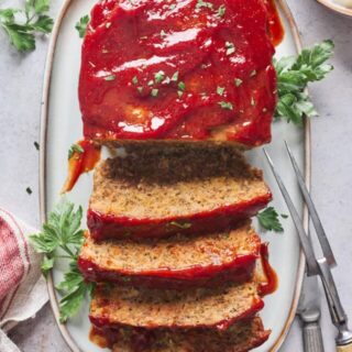 A perfect meatloaf recipe on a white serving platter with slices cut to serve