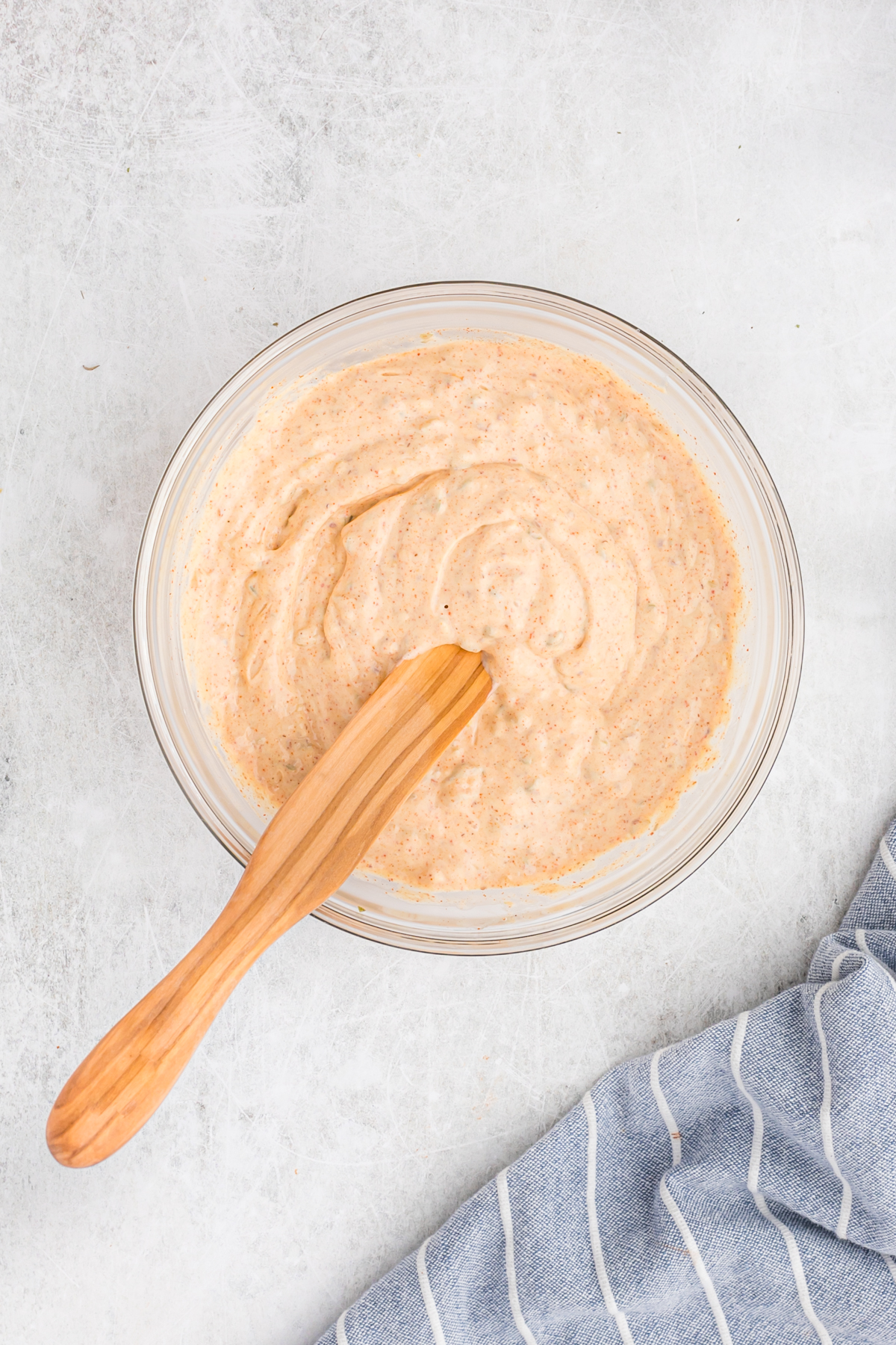 A clear bowl filled with remoulade sauce after stirring with a wooden spoon