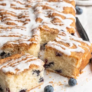 Slices of a blueberry coffee cake recipe ready to serve with fresh blueberries on parchment paper