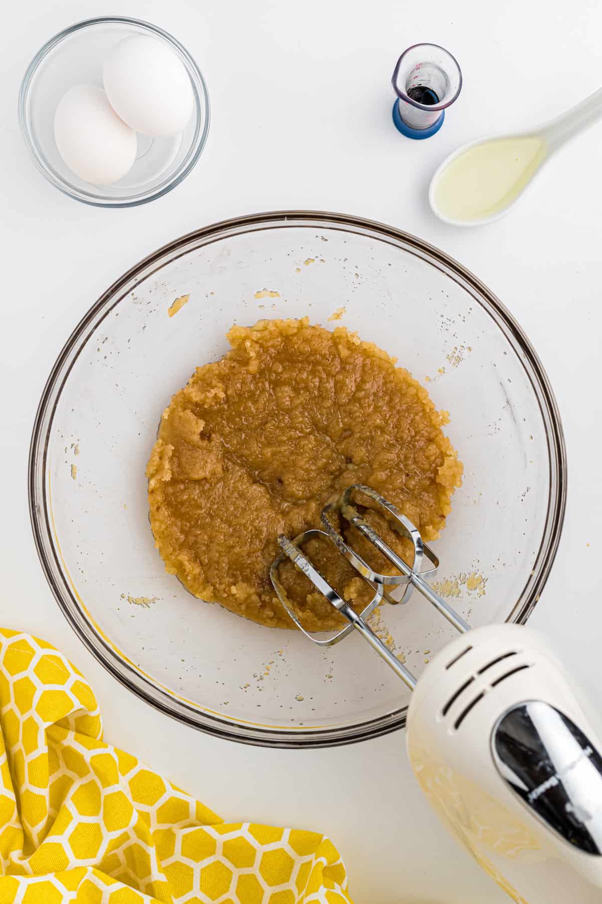 Melted butter and sugars being mixed together with a hand mixer