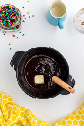 A pot of chocolate frosting being whisked together with butter
