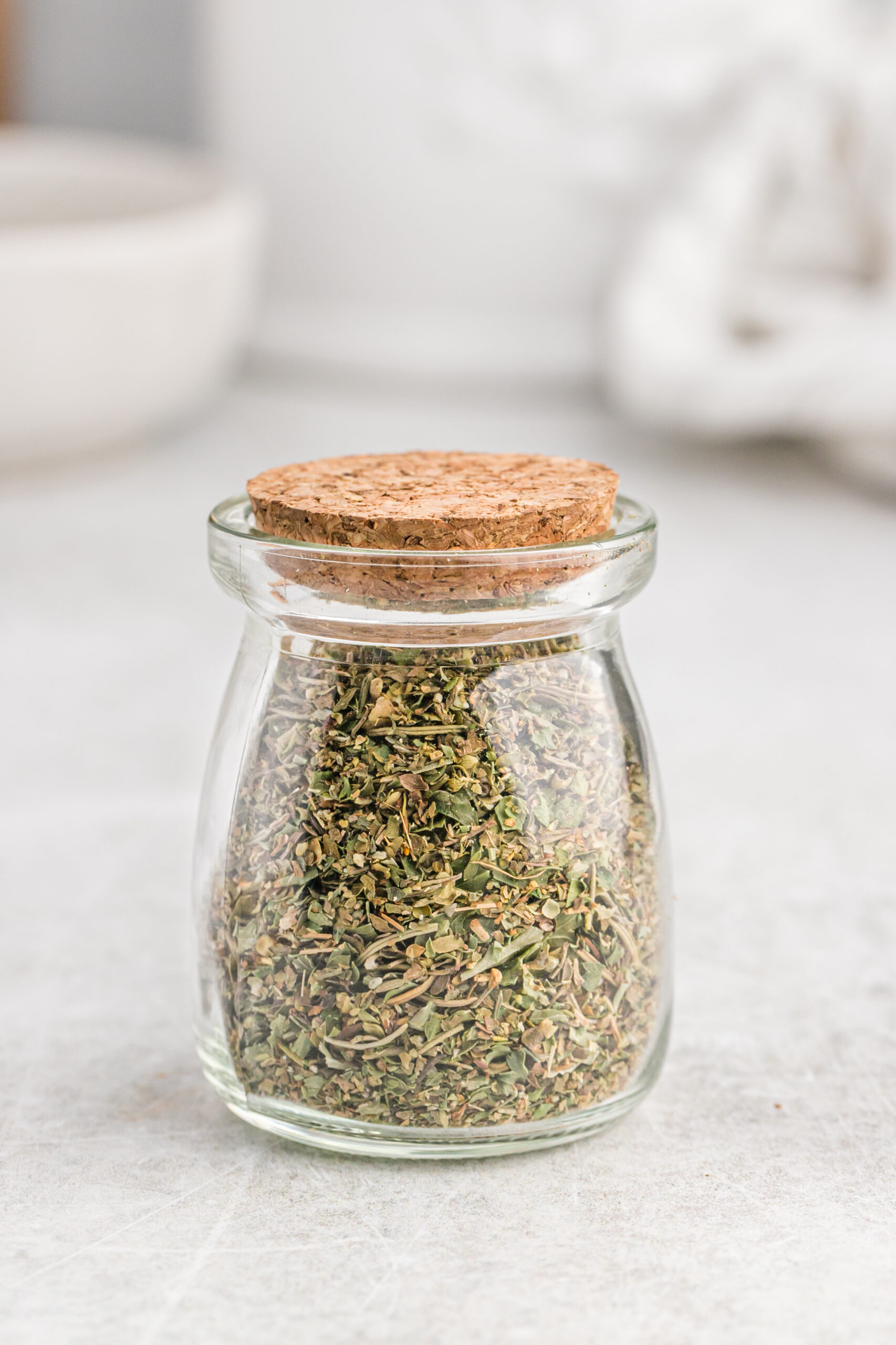 Italian seasoning in a glass canister with a tight cork lid