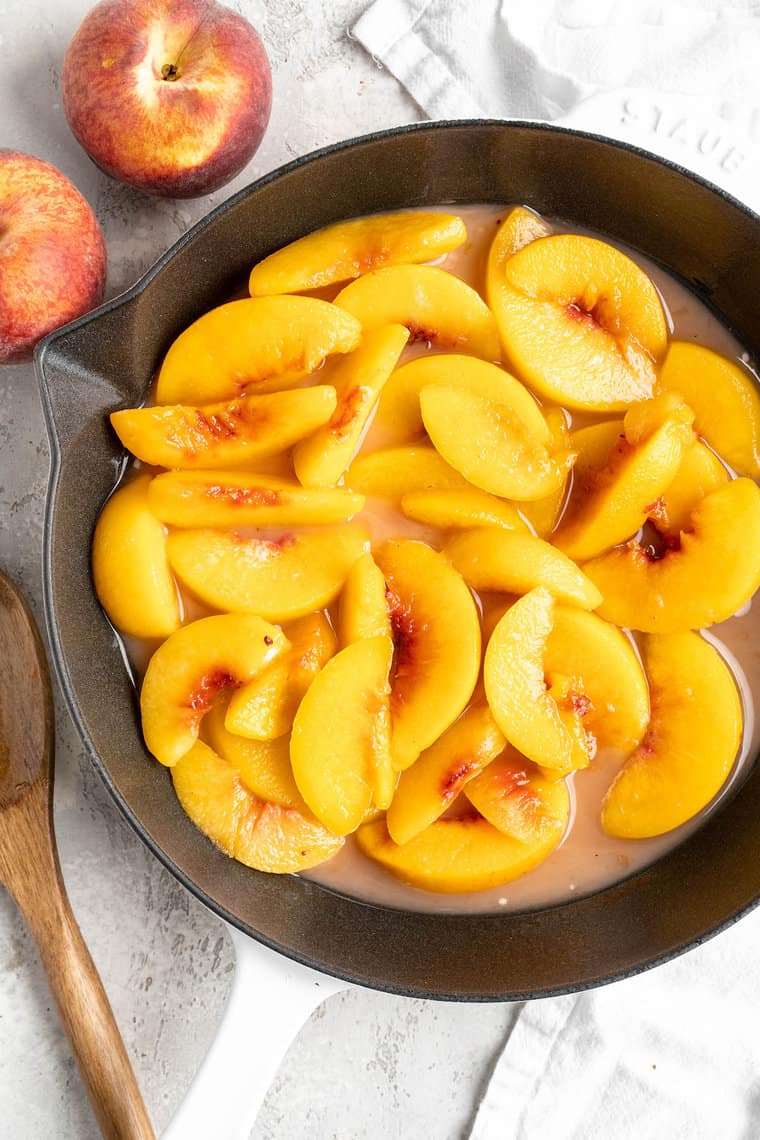 Peach slices added to a cast iron skillet