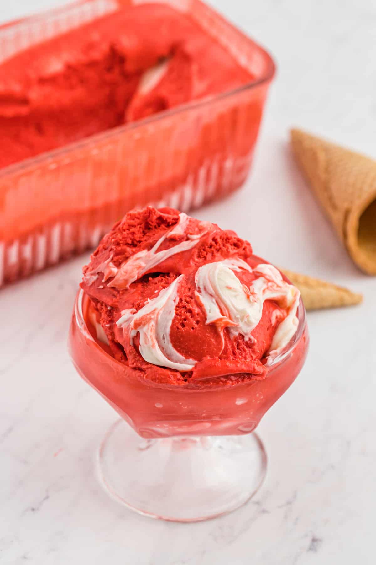 Red velvet ice cream in a glass with a swirl of cream cheese inside