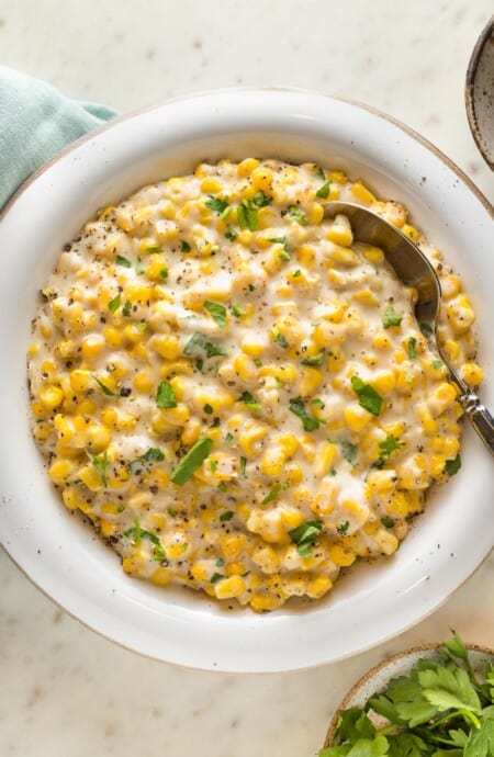 A close up of homemade cream corn recipe ready to serve with a spoon to enjoy
