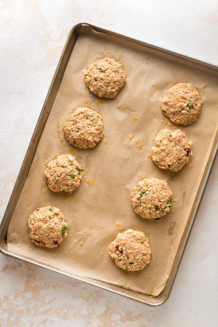 8 Salmon cakes on a parchment lined baking sheet.