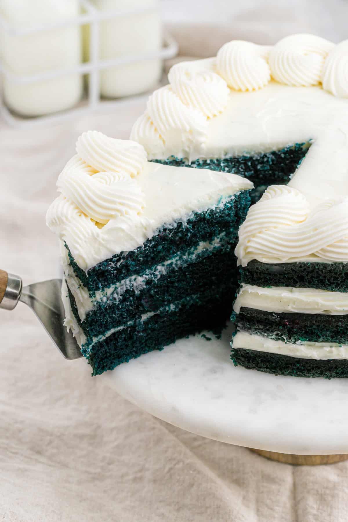 a slice of blue red velvet cake pulling out of the layer cake