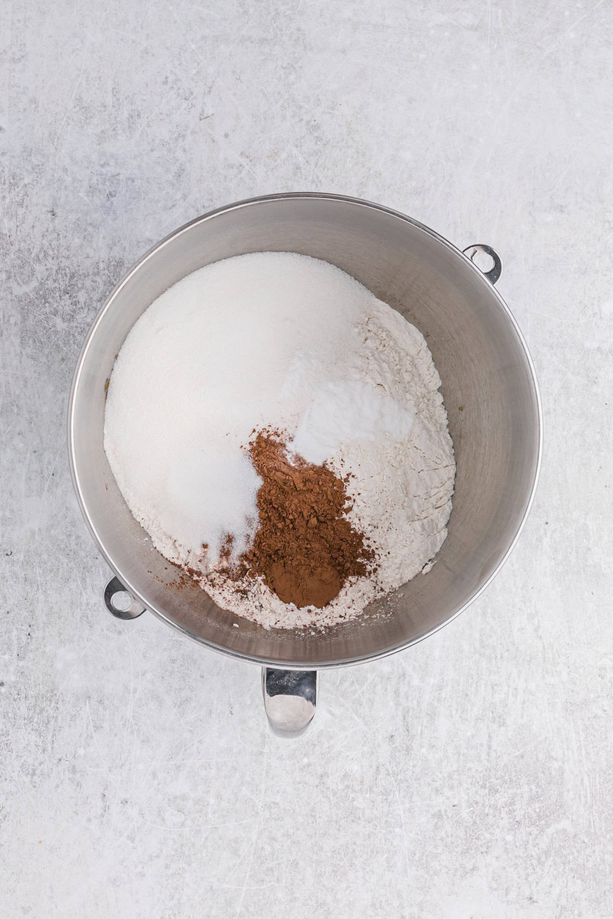 Dry cake ingredients of flour and cocoa powder in a stand mixer bowl on gray countertop