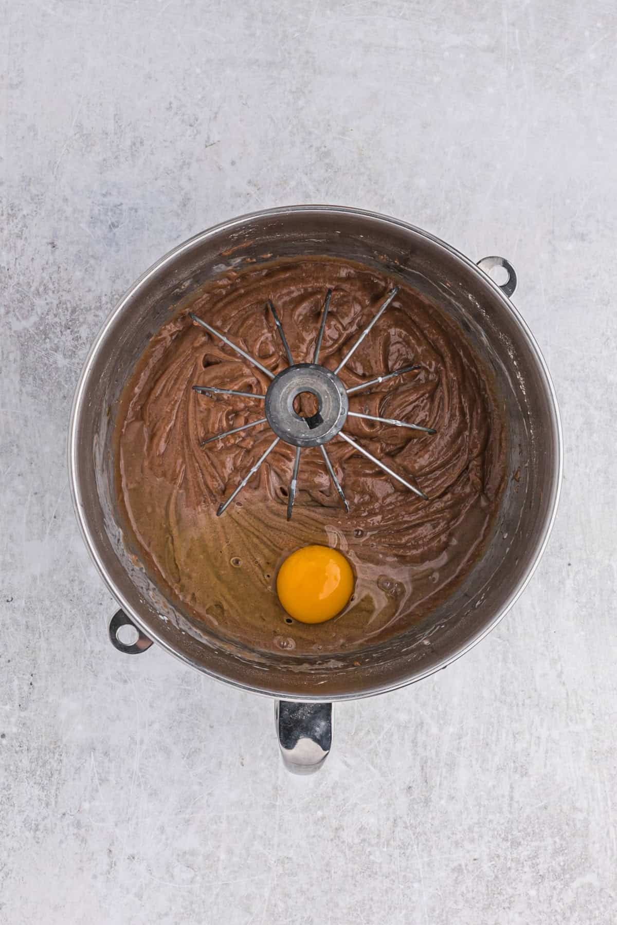 Eggs added to a cocoa hinted velvet cake batter in stand mixer