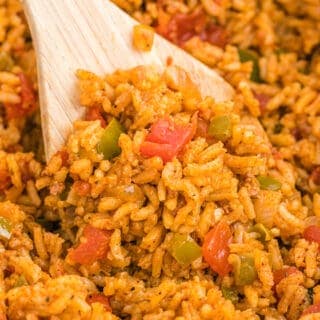 A close up of a wooden spoon of mexican rice being served