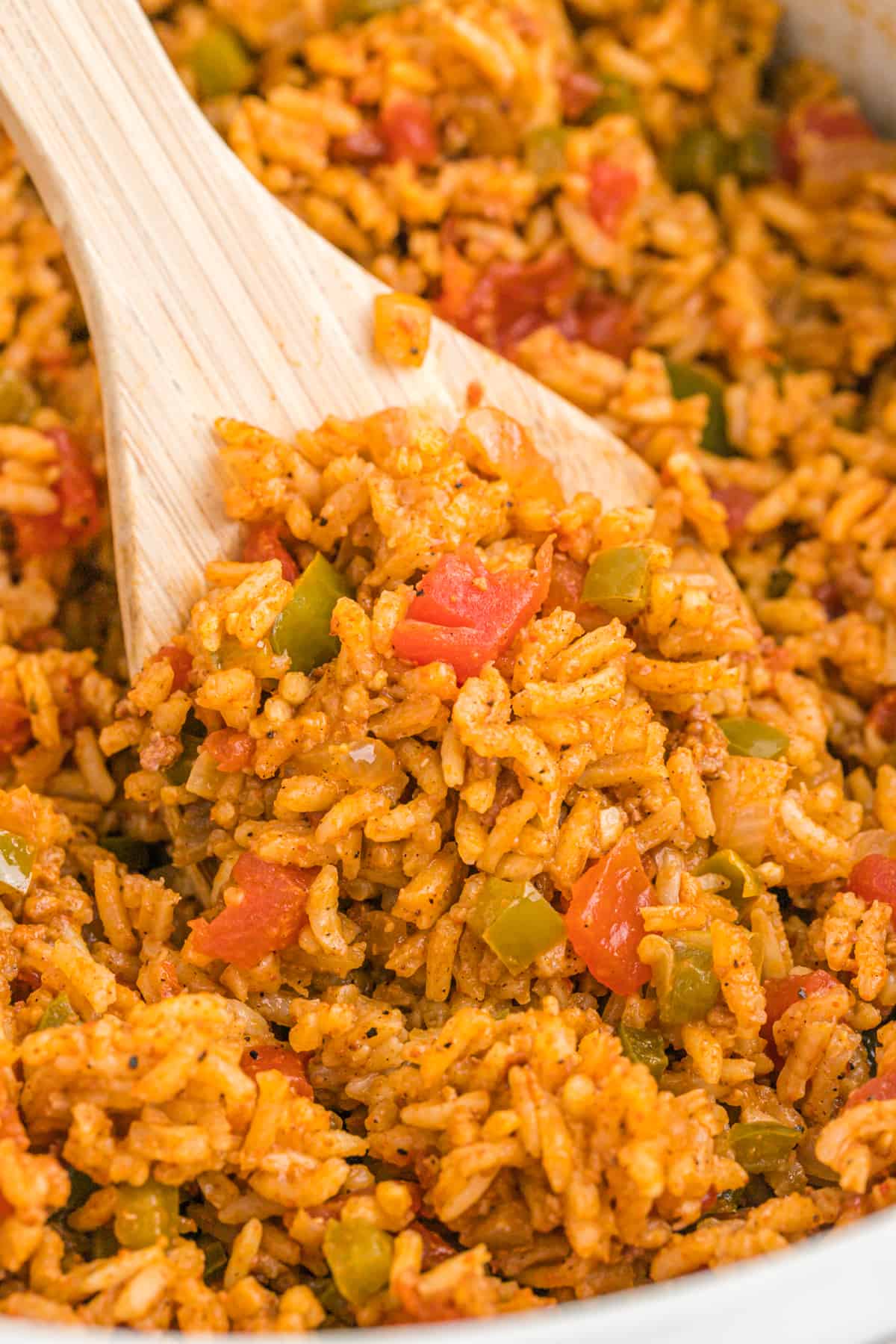 A close up of a wooden spoon of mexican rice being served