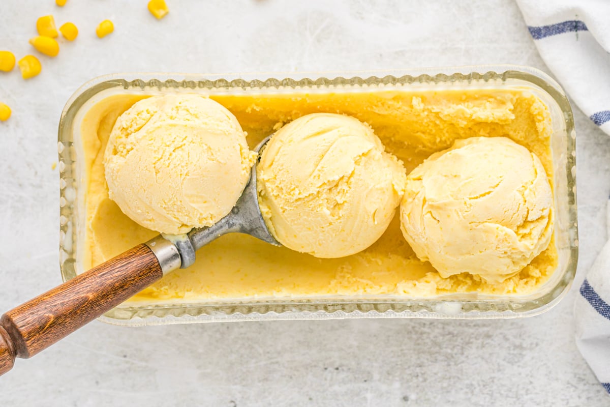 Three scoops of a corn ice cream recipe in a canister ready to scoop and serve