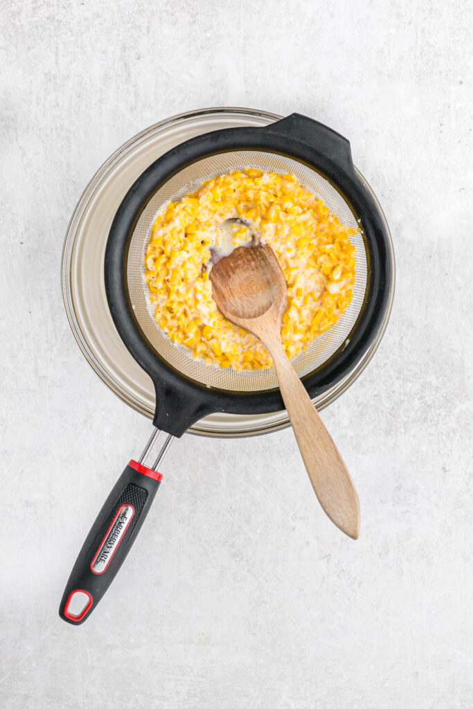 Sweet corn ice cream puree being sieved through a strainer