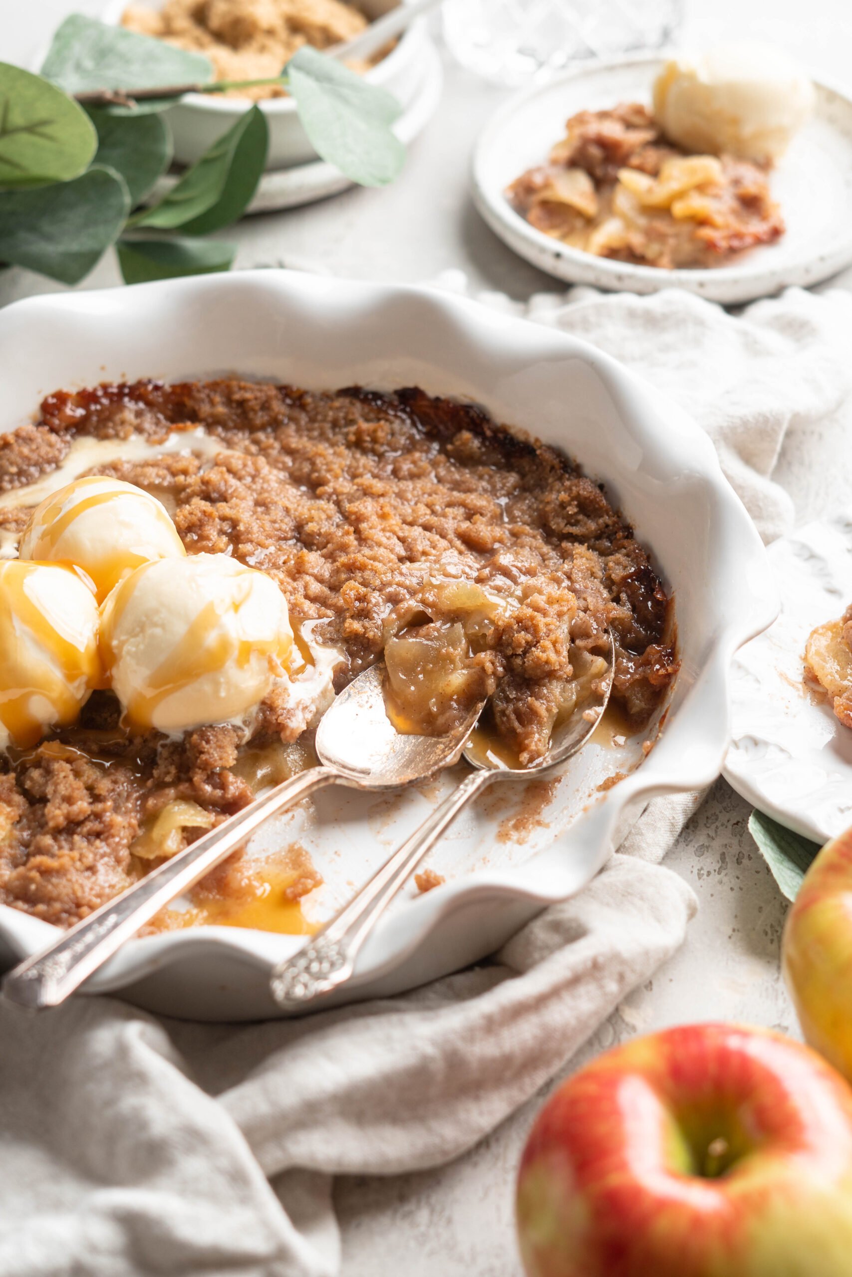 An apple brown betty being served with two spoons scooping some out