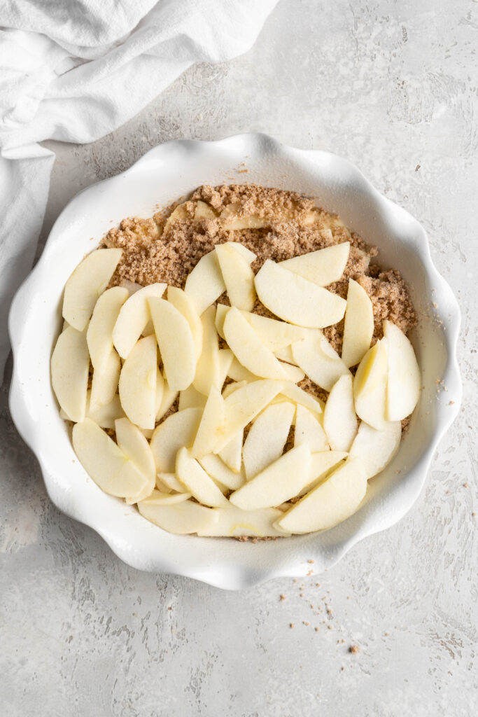 Slices of apple on top of a crumble in a pie dish