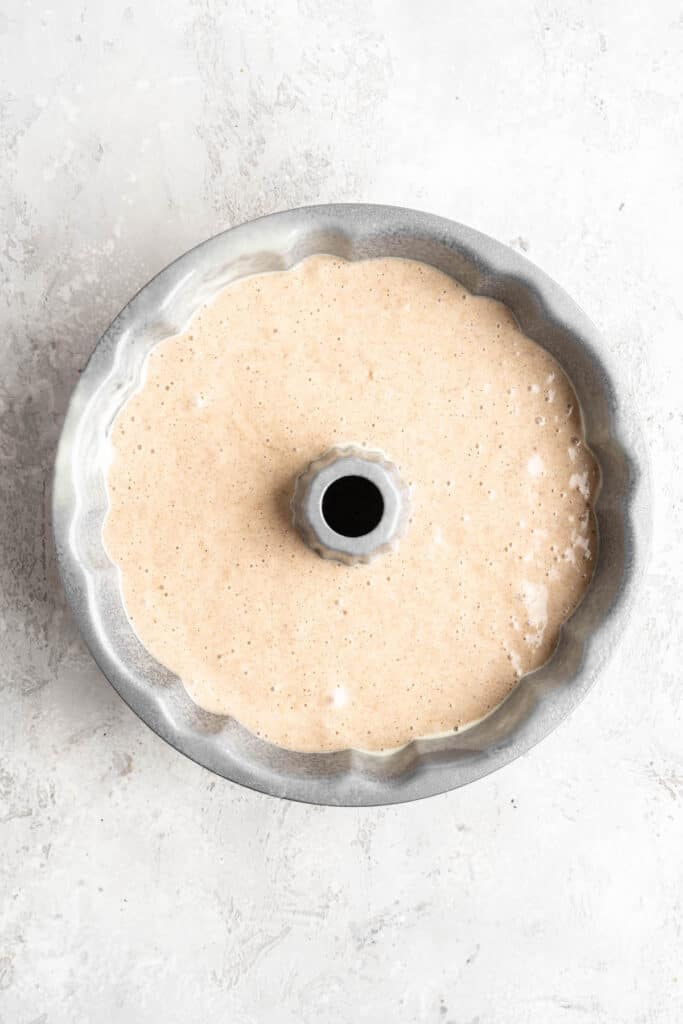 Batter in a bundt pan before baking on a white countertop
