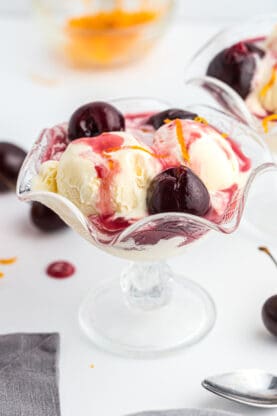 A glass of vanilla ice cream topped with cherries jubilee ready to serve