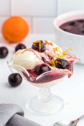 A glass of ice cream with a cherries jubilee ready to serve