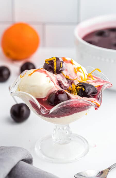 A glass of ice cream with a cherries jubilee ready to serve