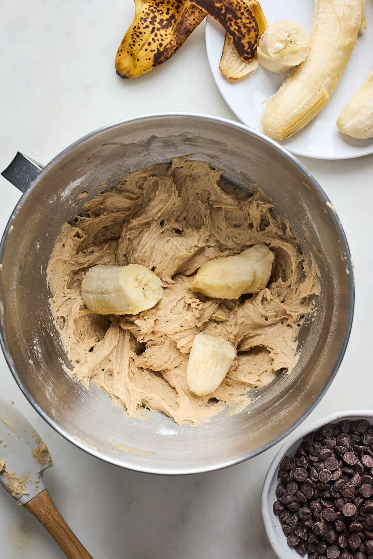 Ripe banana pieces in a bread batter in a mixing bowl