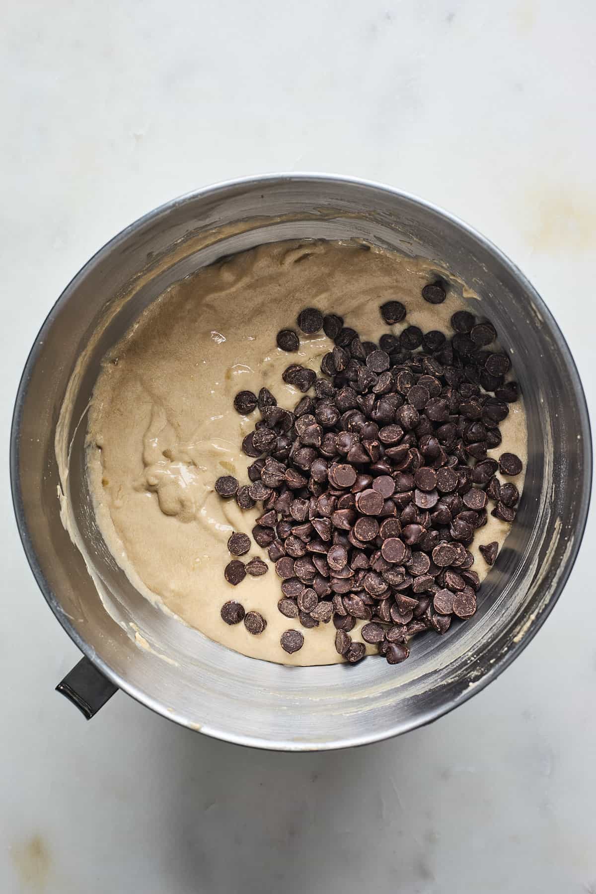 A chocolate banana bread batter with chocolate chips on top before mixing together