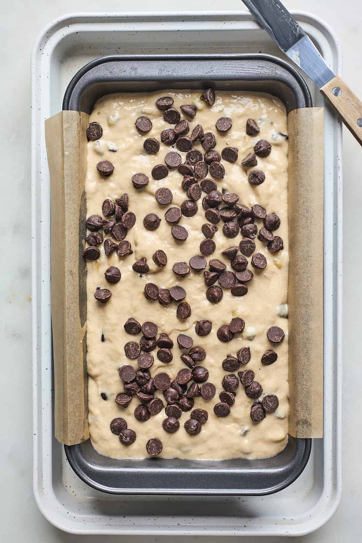 Banana bread batter in a loaf pan with chocolate chips on top