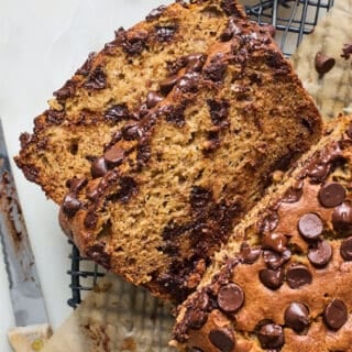 Two slices of chocolate chip banana bread cut from a large loaf on a wire rack