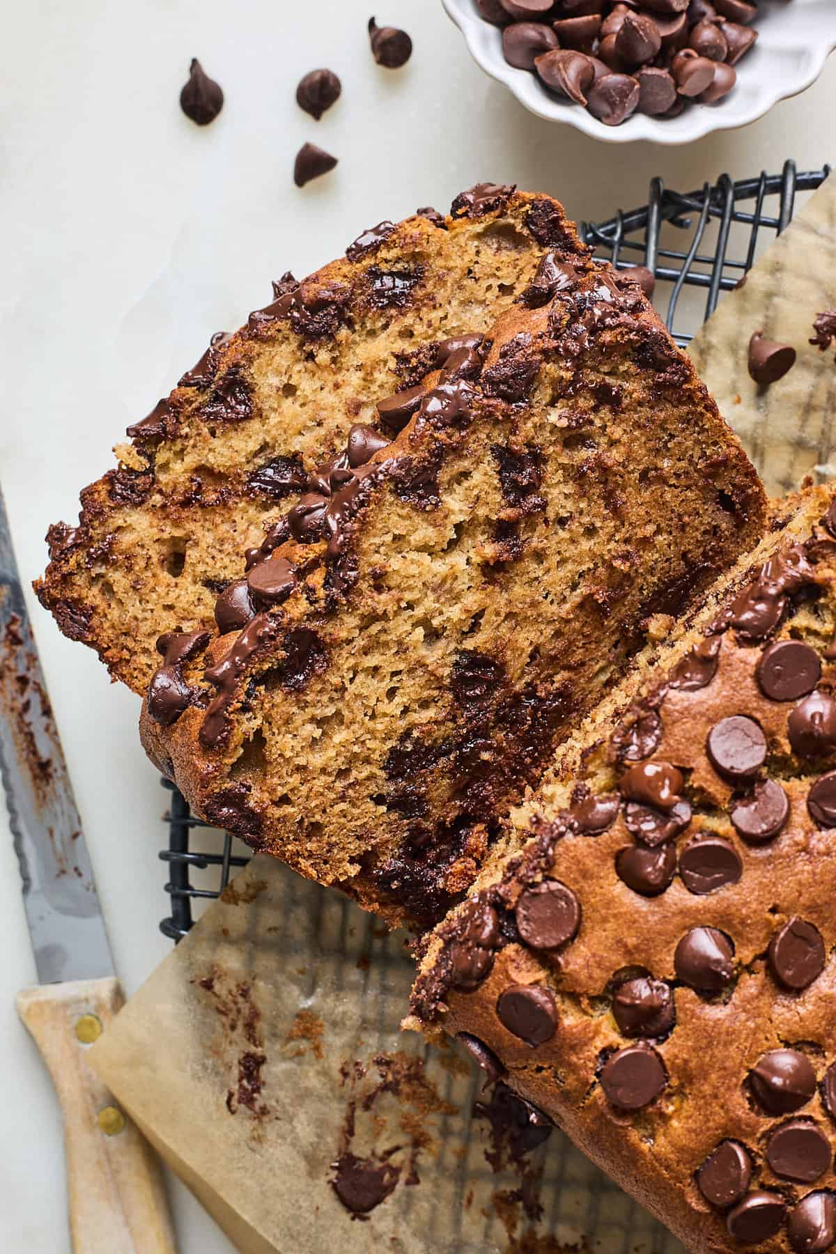 Two slices of chocolate chip banana bread cut from a large loaf on a wire rack