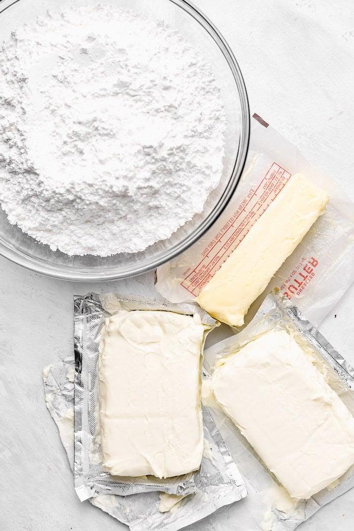 Butter, cream cheese and powdered sugar on a bowl on white countertop