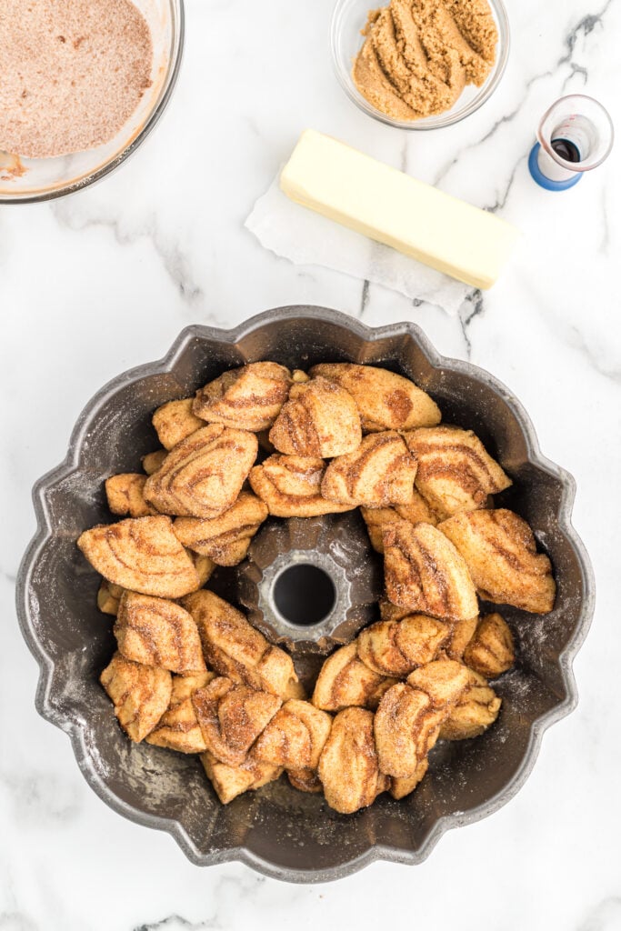 Cinnamon roll dough pieced together in a greased bundt pan