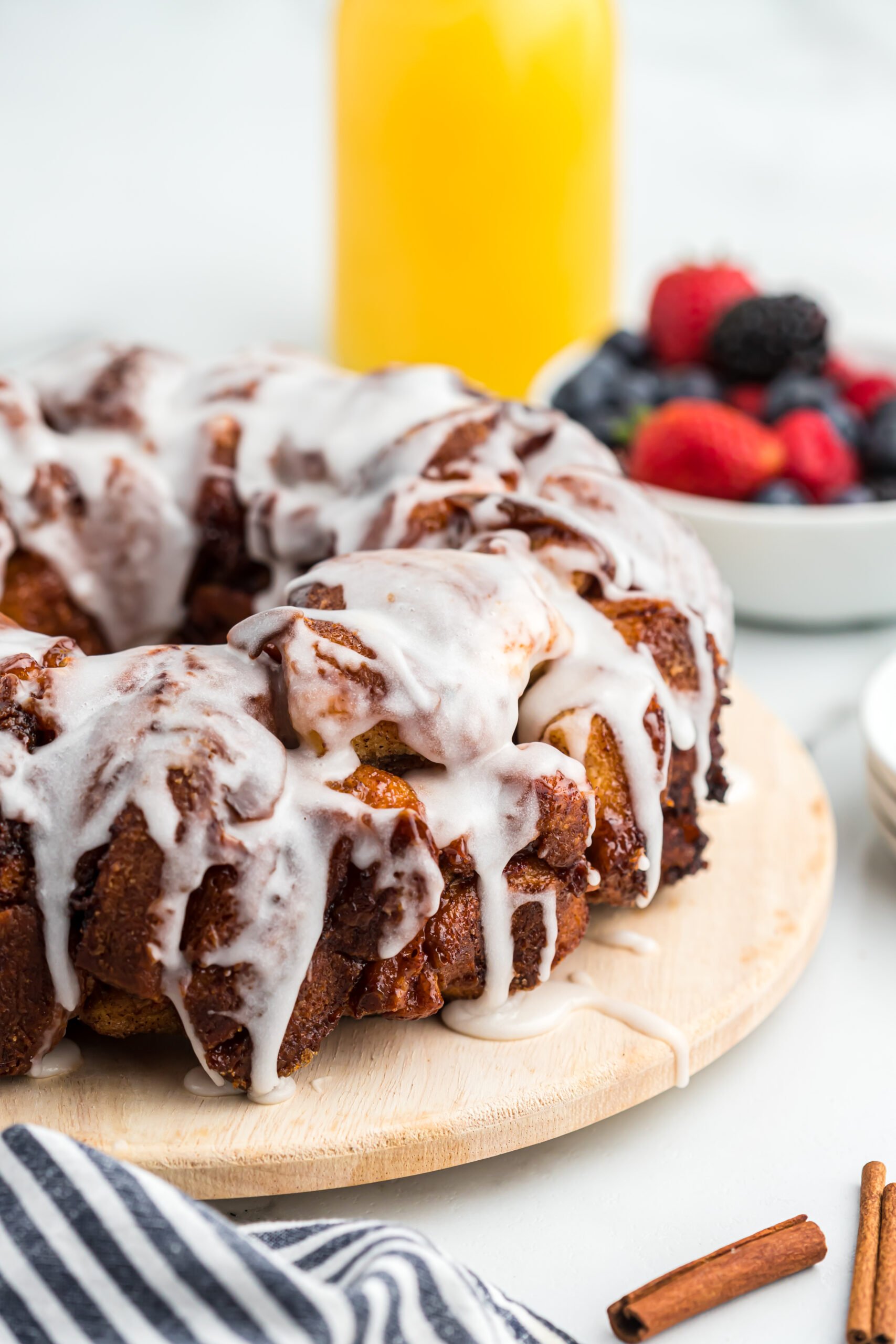 A close up of a delicious cinnamon roll monkey bread with fresh berries in the background