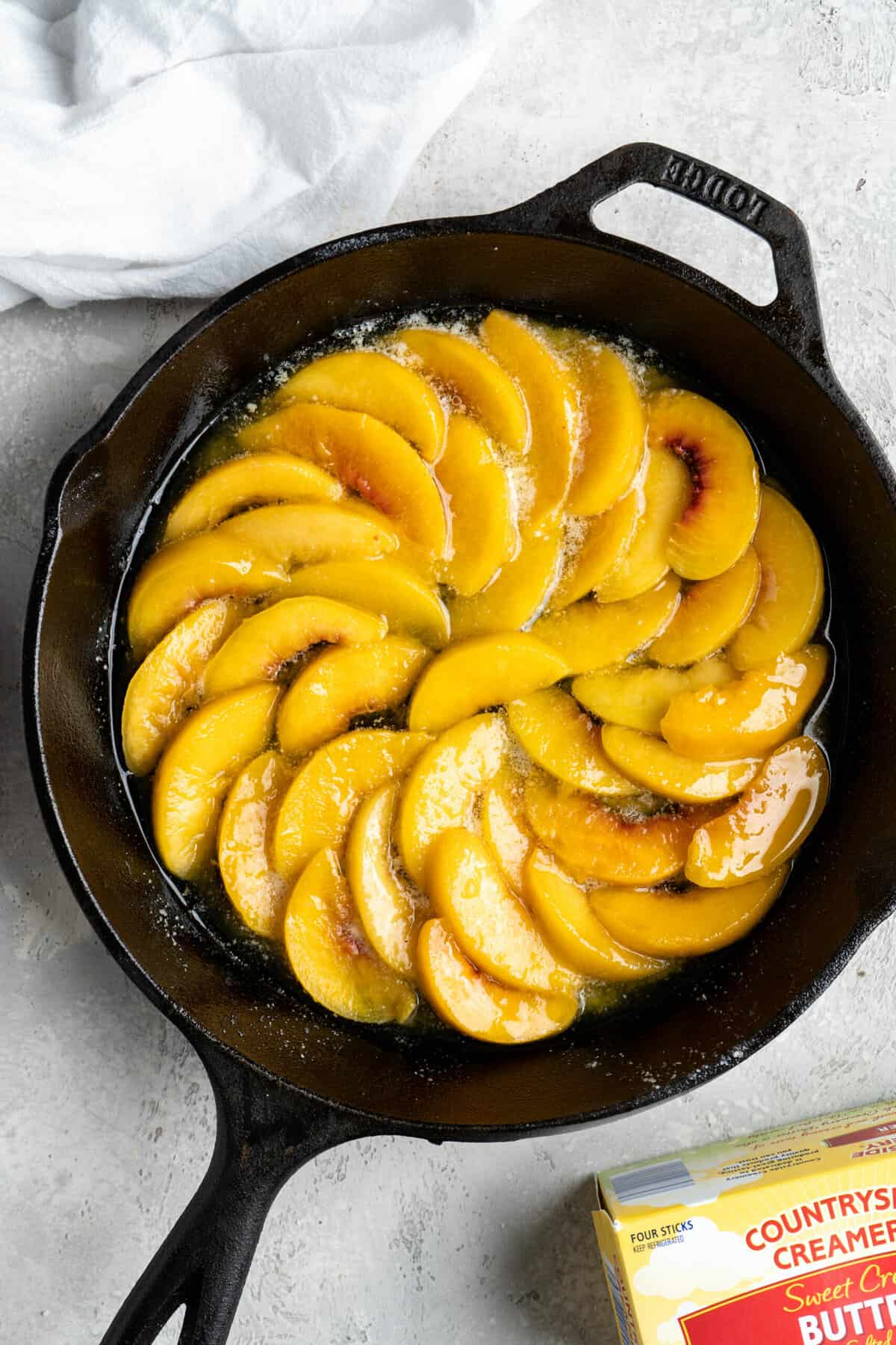 Peach slices placed on the bottom of a cast iron skillet